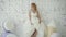 Cute young blonde woman in wedding dress posing and dancing in studio on background huge ice cream and macaroni