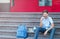 Cute, young boy in blue shirt with backpack holds globe in his hands on the steps in front of his school. Education