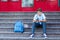 Cute, young boy in blue shirt with backpack holds globe in his hands on the steps in front of his school. Education