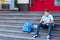 Cute, young boy in blue shirt with backpack holds globe in his hands on the steps in front of his school. Education,