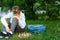 Cute young boy in blue shirt plays chess on grass in park, outdoor. Hobby, education,