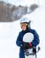 Cute young boy in gray helmet and orange googles, in blue jacket holds snowboard on white snow background. winter sport