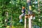 Cute young boy in helmet with climbing equipment in the rope amusement park. Summer camp,