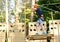 Cute young boy in helmet with climbing equipment in the rope amusement park. Summer camp, holidays