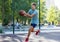 A cute young boy plays basketball on the street playground in summer. Teenager in a green t-shirt with orange basketball ball