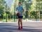 A cute young boy plays basketball on the street playground in summer. Teenager in a green t-shirt with orange basketball ball