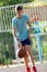 A cute young boy plays basketball on the street playground in summer. Teenager in a green t-shirt with orange basketball ball