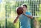 A cute young boy plays basketball on the street playground in summer. Teenager in a green t-shirt with orange basketball ball