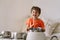 Cute young boy using wooden sticks to bang saucepans that are set up like a drumset