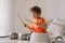 Cute young boy using wooden sticks to bang saucepans that are set up like a drumset