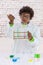 Cute young boy wearing scientist coat doing science experiment with test tube over a wall