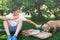 Cute, young boy in white t shirt sits on the grass and takes a slice of pizza in the summer park. Boy eats pizza