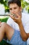 Cute, young boy in white t shirt sits on the grass and takes a slice of pizza in the summer park. Boy eats pizza