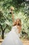 Cute young bride with long hairs holding her wedding bouquet includes white roses and other flowers. Beautiful white marriage