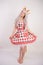 Cute young caucasian girl in kitchen plaid apron with fluffy Fox ears and long fur red tail standing barefoot on white background