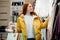 Cute young caucasian woman choosing clothes in shopping store