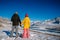 Cute young couple in bright down jackets on the backdrop of beautiful winter mountain scenery with copy space. Christmas holidays