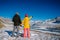 Cute young couple in bright down jackets on the backdrop of beautiful winter mountain scenery with copy space. Christmas holidays