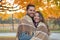 Cute young couple wrapped in a cozy blanket at the park