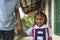 A cute young Filipino girl in a white a blue school uniform, being fetched by her grandfather right after class at a provincial