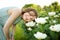 Cute young girl admiring tall white peonies on sunny summer day. Child and flowers, summer, nature and fun