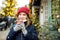 Cute young girl drinking hot chocolate on traditional Christmas fair in Riga, Latvia. Child enjoying sweets, candies and