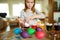 Cute young girl dyeing Easter eggs at home. Child painting colorful eggs for Easter hunt. Kid getting ready for Easter celebration