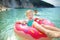 Cute young girl floating on toy ring at Myrtos beach, the most famous and beautiful beach of Kefalonia, a large coast with