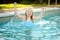 Cute young girl having fun in outdoor pool. Child learning to swim. Kid having fun with water toys. Family fun in a pool. Summer