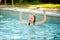 Cute young girl having fun in outdoor pool. Child learning to swim. Kid having fun with water toys. Family fun in a pool. Summer