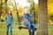 Cute young girl having fun on a swing in sunny autumn park. Family weekend in a city