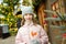 Cute young girl having rooster-shaped lollipop on traditional Christmas fair in Riga, Latvia. Child enjoying sweets, candies and