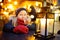 Cute young girl having rooster-shaped lollipop on traditional Christmas fair in Riga, Latvia. Child enjoying sweets, candies and