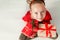 Cute young girl holding christmas presents, smiling and looking at camera. Happy kid at christmas time sitting on the floor.