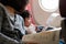 Cute young girl looking at flight safety card with her mom on the airplane flight. Safety on board