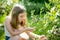 Cute young girl picking fresh berries on organic blueberry farm on warm and sunny summer day. Fresh healthy organic food