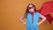 Cute young girl play superhero on a orange background background