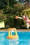 cute young girl playing with inflatable basketball hoop in swimming pool