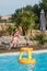 cute young girl playing with inflatable basketball hoop in swimming pool