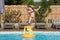 cute young girl playing with inflatable basketball hoop in swimming pool