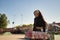 Cute young girl with punk style and heterochromia holding a skateboard with her hands behind her back in a skateboard park