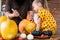 Cute young girl sitting on kitchen table, helping her father to carve large pumpkin. Halloween family background.