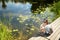 Cute young girl sitting on a pier by Pastovis lake in Moletai town, one of the oldest settlements in Lithuania and a popular