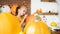 Cute young girl sitting at a table in living room, drawing a face on a large halloween pumpkin.