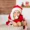 Cute young girl wearing santa hat hugging her christmas present, soft toy teddy bear. Happy kid with xmas present, smiling.