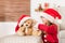 Cute young girl wearing santa hat playing with her christmas present, soft toy teddy bear. Playful kid at christmas time.