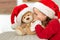 Cute young girl wearing santa hat whispering a secret to her teddy bear christmas present toy. Kid sharing secrets with teddy bear