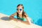 Cute young girl wearing swimming goggles having fun in outdoor pool. Child learning to swim. Kid having fun with water toys