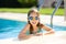 Cute young girl wearing swimming goggles having fun in outdoor pool. Child learning to swim. Kid having fun with water toys