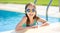 Cute young girl wearing swimming goggles having fun in outdoor pool. Child learning to swim. Kid having fun with water toys